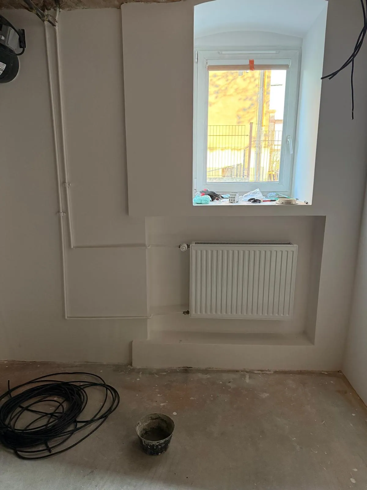 Nowy grzejnik pod oknem w odnowionym pomieszczeniu